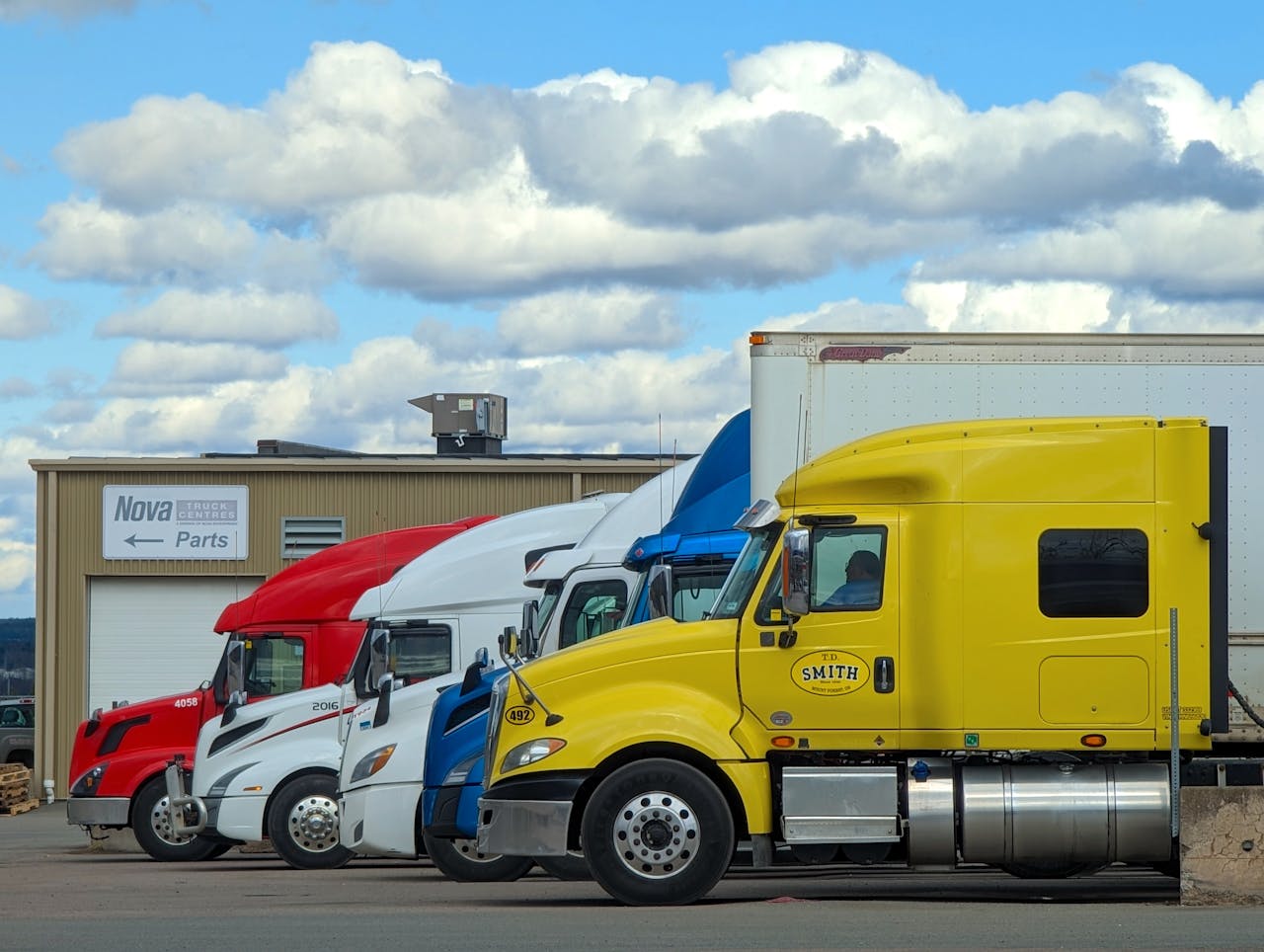 A vibrant lineup of semi trucks parked outside a Nova Truck Center in Truro, NS, Canada.